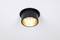A round, black ceiling light with warm illumination, mounted on a white ceiling. It shines directly downwards.