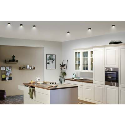 Modern kitchen with white furnishings, an island and built-in appliances. Decorative shelves on the wall, subdued lighting.