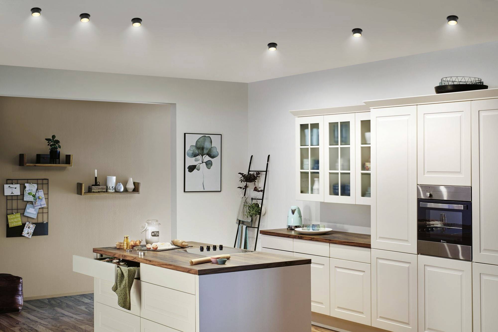 Modern kitchen with cream-coloured cabinets, integrated appliances, and a central island with a wooden worktop.
