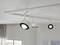 Two ceiling spotlights in a modern design are mounted on a metal track fixed to a light-coloured ceiling.
