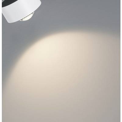 A ray of light from a ceiling light illuminates a grey wall.