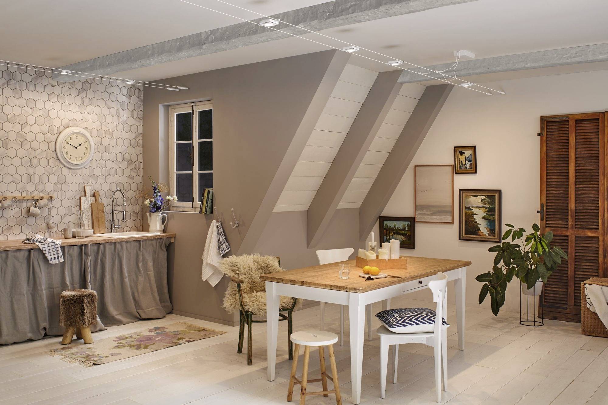 Cosy, modern kitchen and dining area with a wooden table and white chairs, decorated with plants and wall art. Bright, welcoming atmosphere.