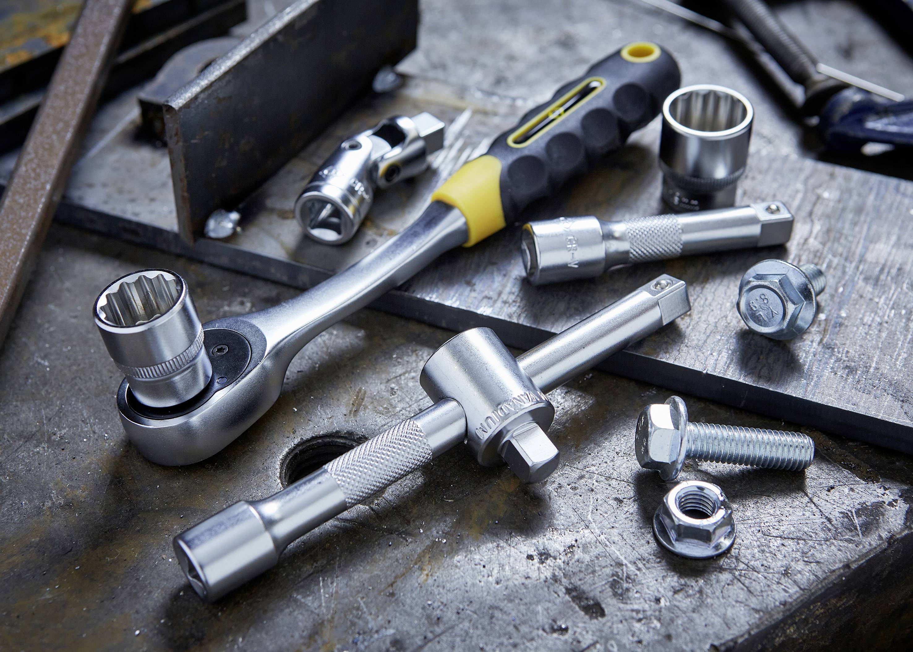 A ratchet tool set lies on a workbench with various sockets and screws, ready for use during repairs.