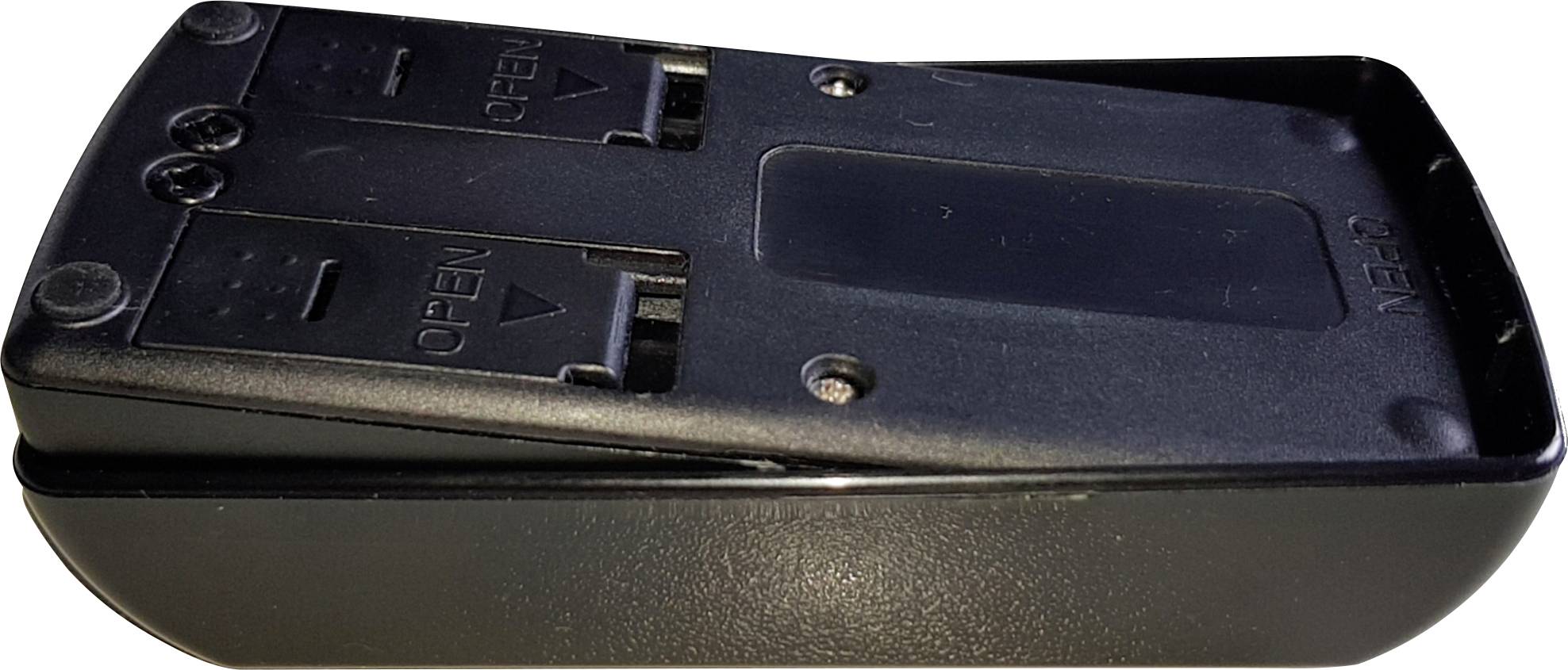 A black TV remote control viewed from below, with two battery compartments and small screws in the corners.