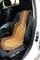 A wooden bead car seat cover is placed on the driver's seat in a white car to increase the comfort of the person sitting.