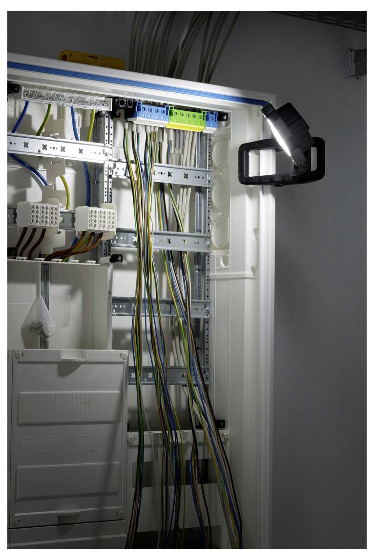 Open electrical control cabinet with rows of terminal blocks and bundled wires illuminated by a work light.<br>