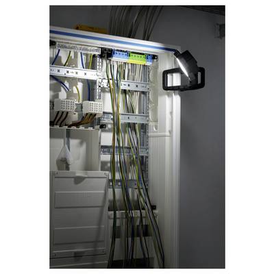 Open electrical control cabinet with rows of terminal blocks and bundled wires illuminated by a work light.<br>
