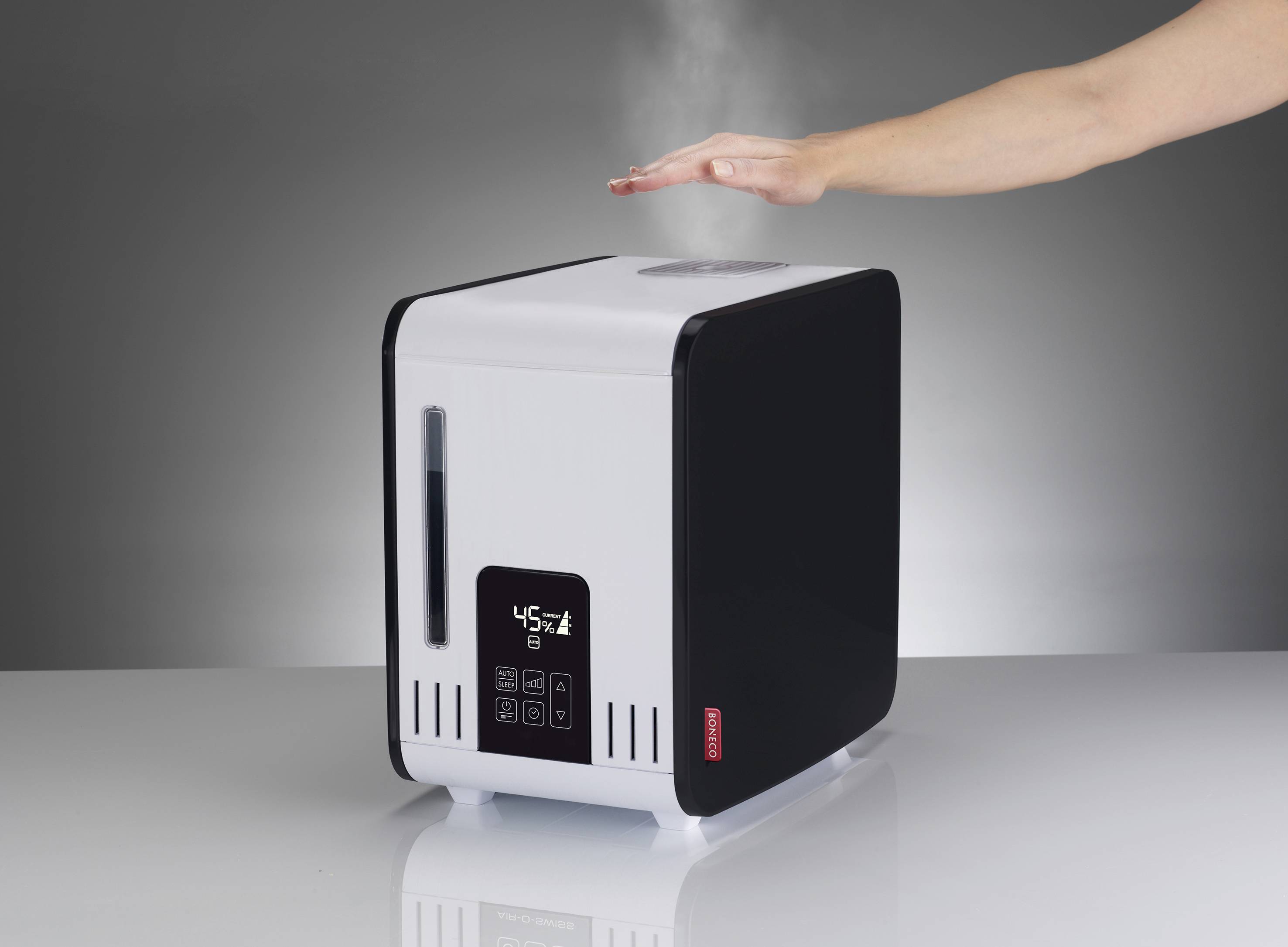 Humidifier with LED display, showing '45%'. Hand testing steam over fan. Device on white table against grey background.