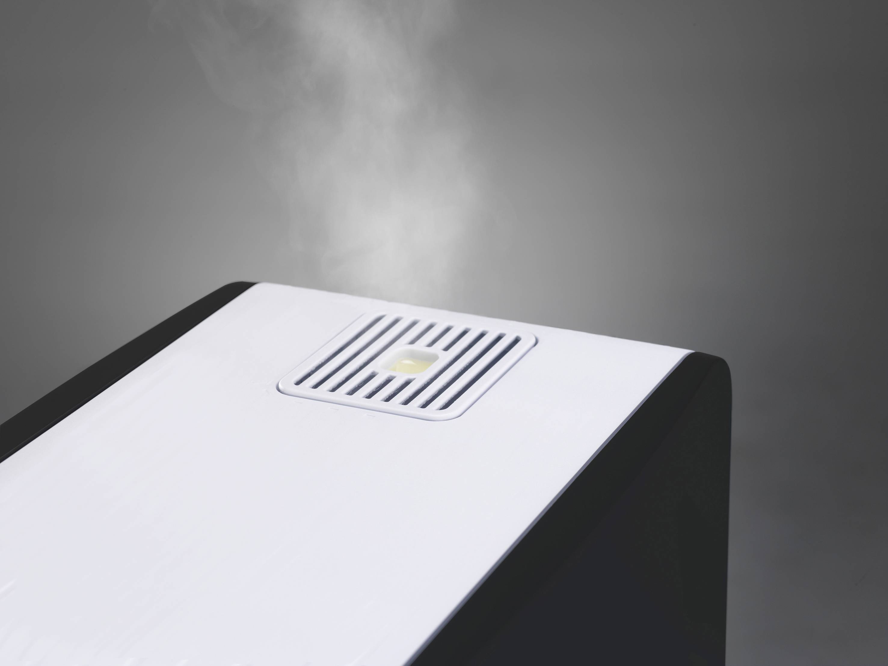A humidifier emitting steam, set against a grey background.