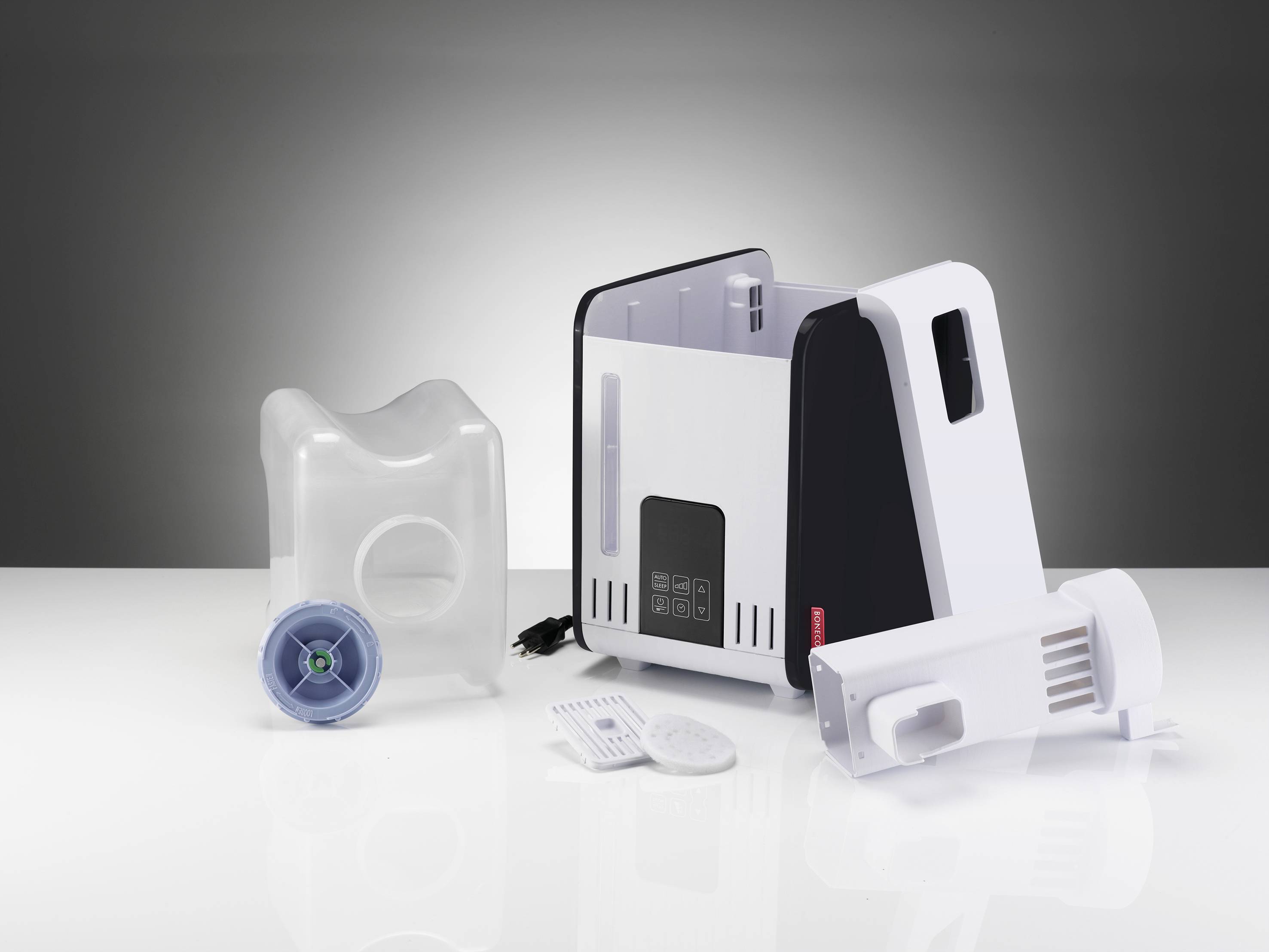 Humidifier with water tank, control panel and accessories such as filter and hygrostat, positioned against a grey background on a white surface.