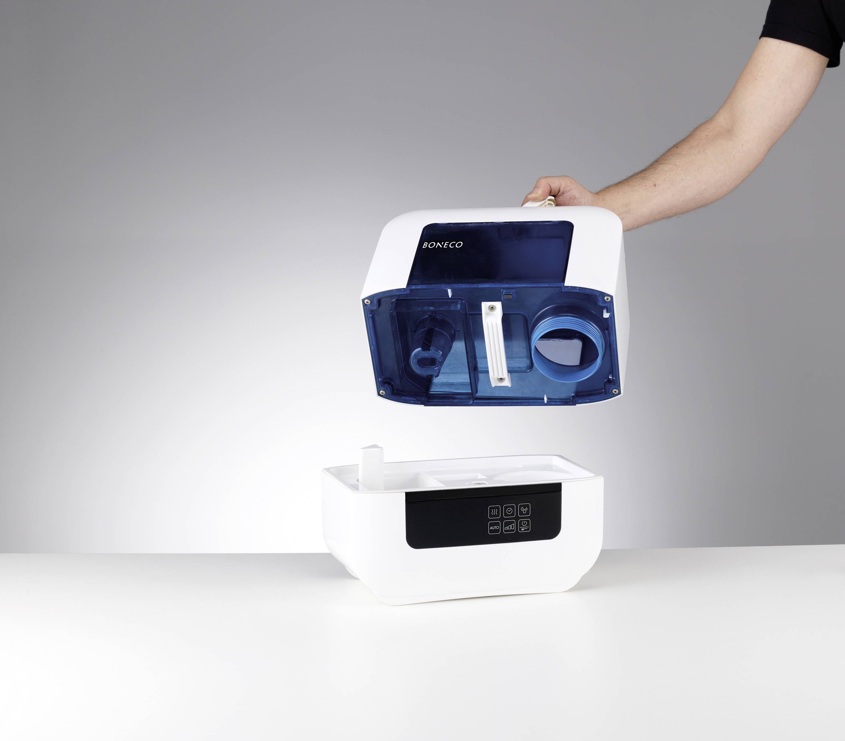 A humidifier is being held by a person in the top right-hand corner. The device is white and blue and has a digital display.