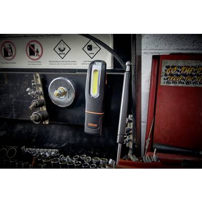 A workshop wall with hooks and clips for tool storage. A torch hangs on a magnet. Tools on the left, a red toolbox on the right.