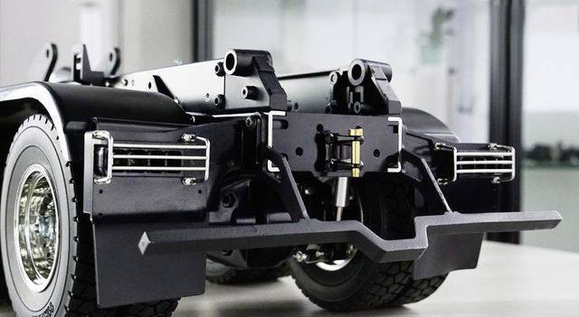 Close-up of a lorry chassis with detailed suspension components and tyres in a workshop setting.