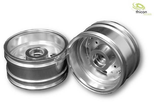 Two silver aluminium alloy wheels stand side by side. The left wheel shows the side without spokes, the right wheel shows the inner side.