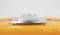 A silver device with a rectangular shape on a glossy, orange surface, possibly a mounting solution.