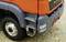 Close-up of an orange lorry with clearly visible steps and tyres on a gravelled surface. The focus is on the details of the steps.