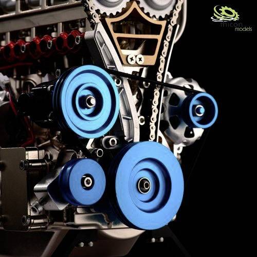 Close-up of a model engine with blue pulleys and visible gears.