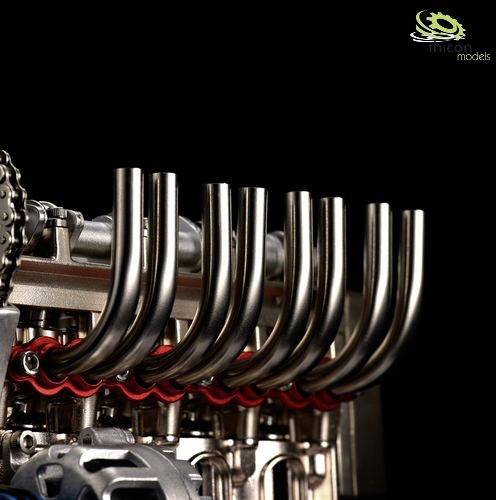 Close-up of an engine with multiple chromed exhaust pipes on a dark background.