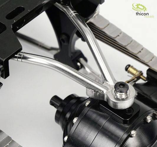 Close-up of a mechanical component with silver metallic linkage and black cylindrical part, potentially part of a model car.