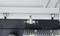 'Close-up of an industrial machine with a moving metallic component above a perforated metal plate.'