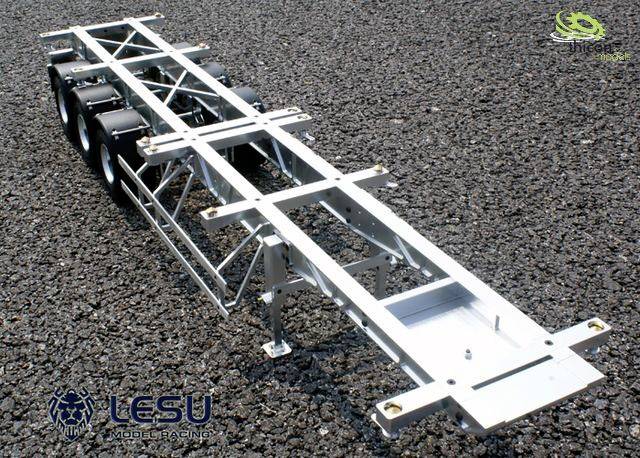 'Payload chassis of a model lorry on gravelly ground, showing metal frame with multiple axles and pivoting suspension.'