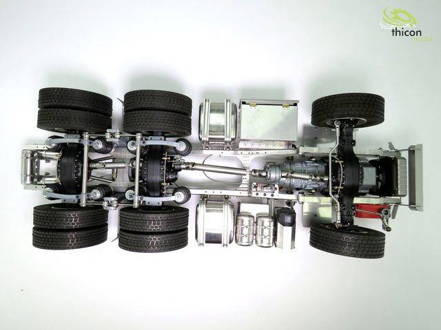 In the image, a metal model of a lorry chassis with detailed mechanics is visible. A logo is depicted in the top right corner.