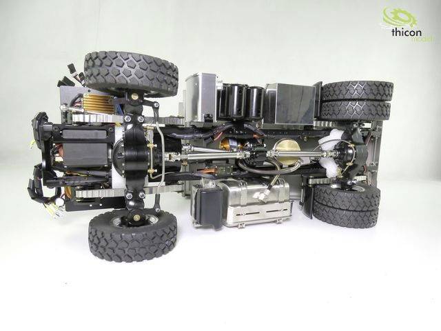 Underside view of a remote-controlled model car reveals the complex electronics and mechanics, including motor and wheels.