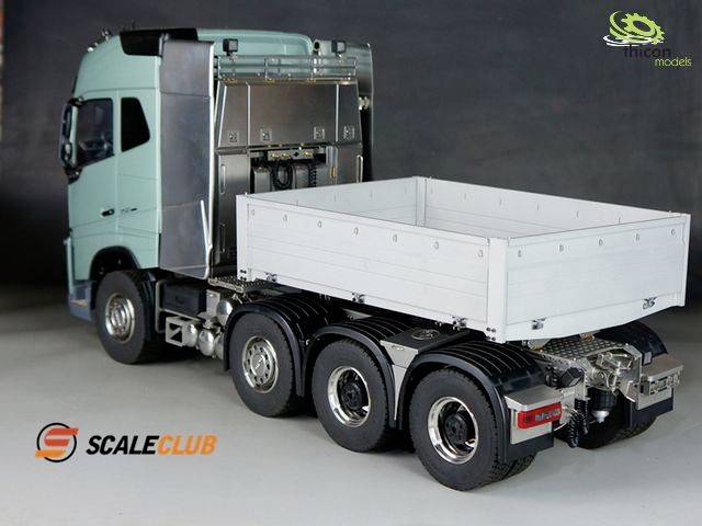 A model lorry with three axles, an open cargo area and a turquoise cab is flanked by the company logos 'ScaleClub' and 'Trickymodels'.