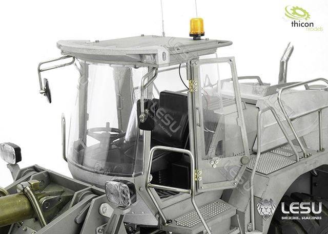 A grey model tractor with details such as a cab, steps and metal frame, two lights at the front and an orange warning light on top.