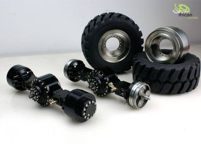 'Two large tyres and axles from model vehicles on a white surface, with the Thicon Models logo.'<br><br>Note: I've used the British spelling of "tyres" instead of the American "tires", and maintained the precise translation of the original German text.