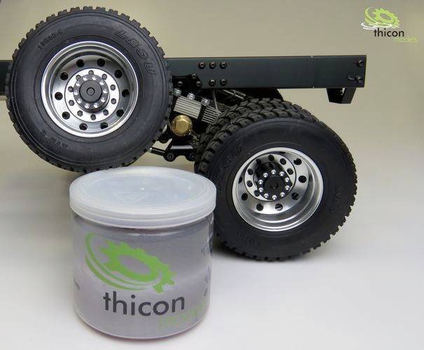 A model vehicle on large tyres stands next to a plastic container with the logo 'thicon models'. The container contains grey matter.