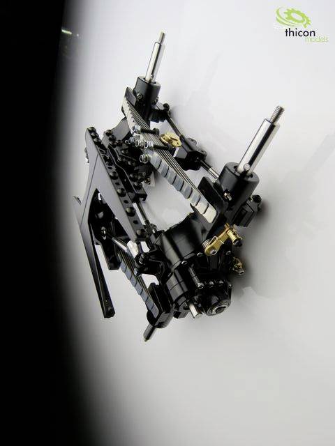 A complex mechanical model made of black and silver metal parts with gears and axles, mounted on a wall.