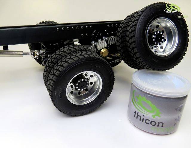 A model lorry chassis with large off-road tyres next to a container labelled 'thicon'.