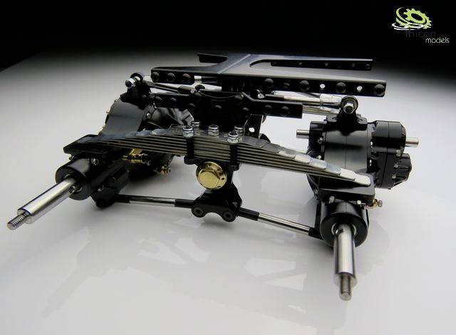 A detailed model of a chassis with metal components, showing suspension and drive axles, on a light background.