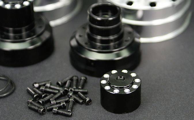 Black metal parts and screws on a black background, mechanical components for technical applications.