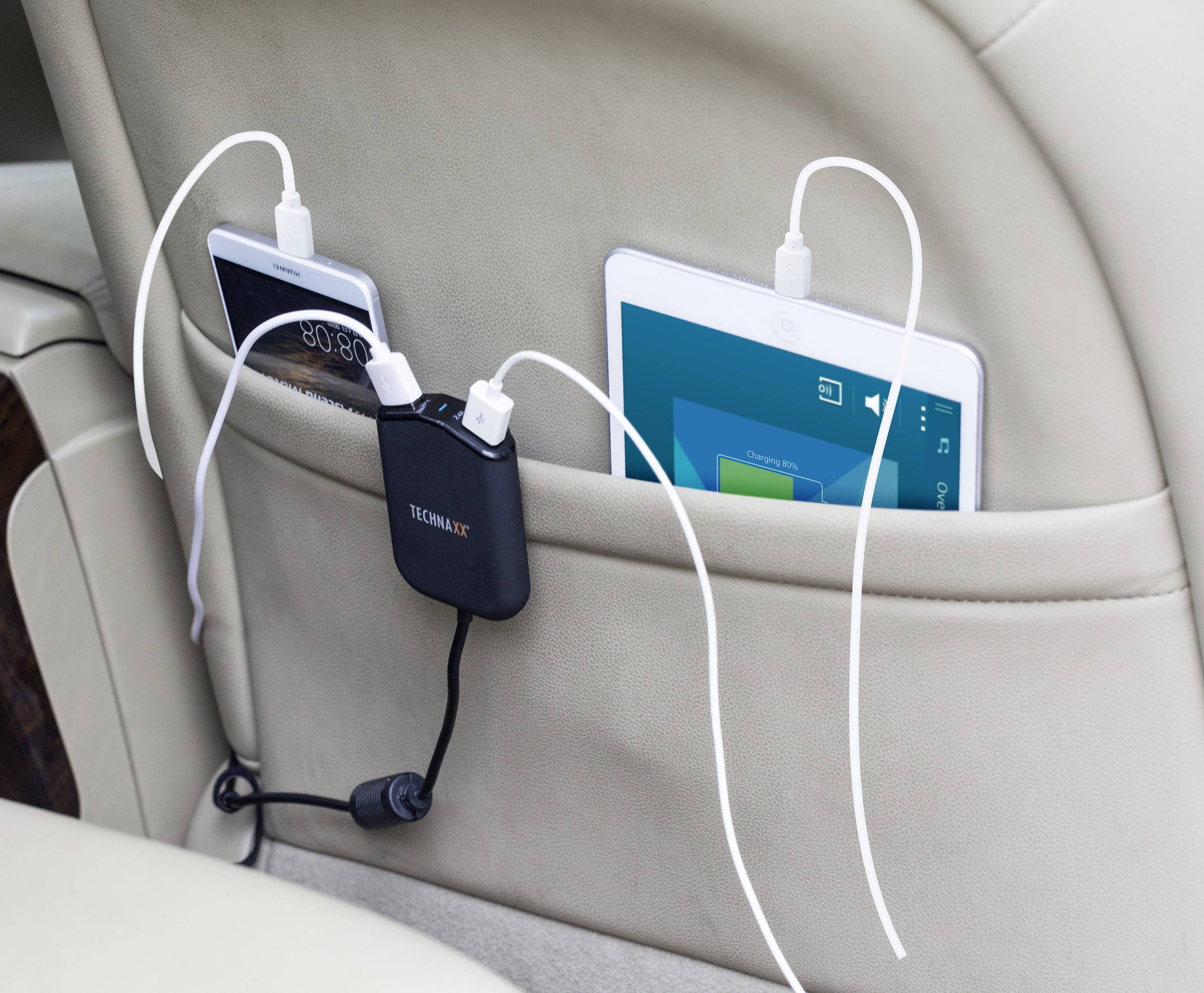 A charger with two USB cables charges a smartphone and a tablet in a car seat storage bag.