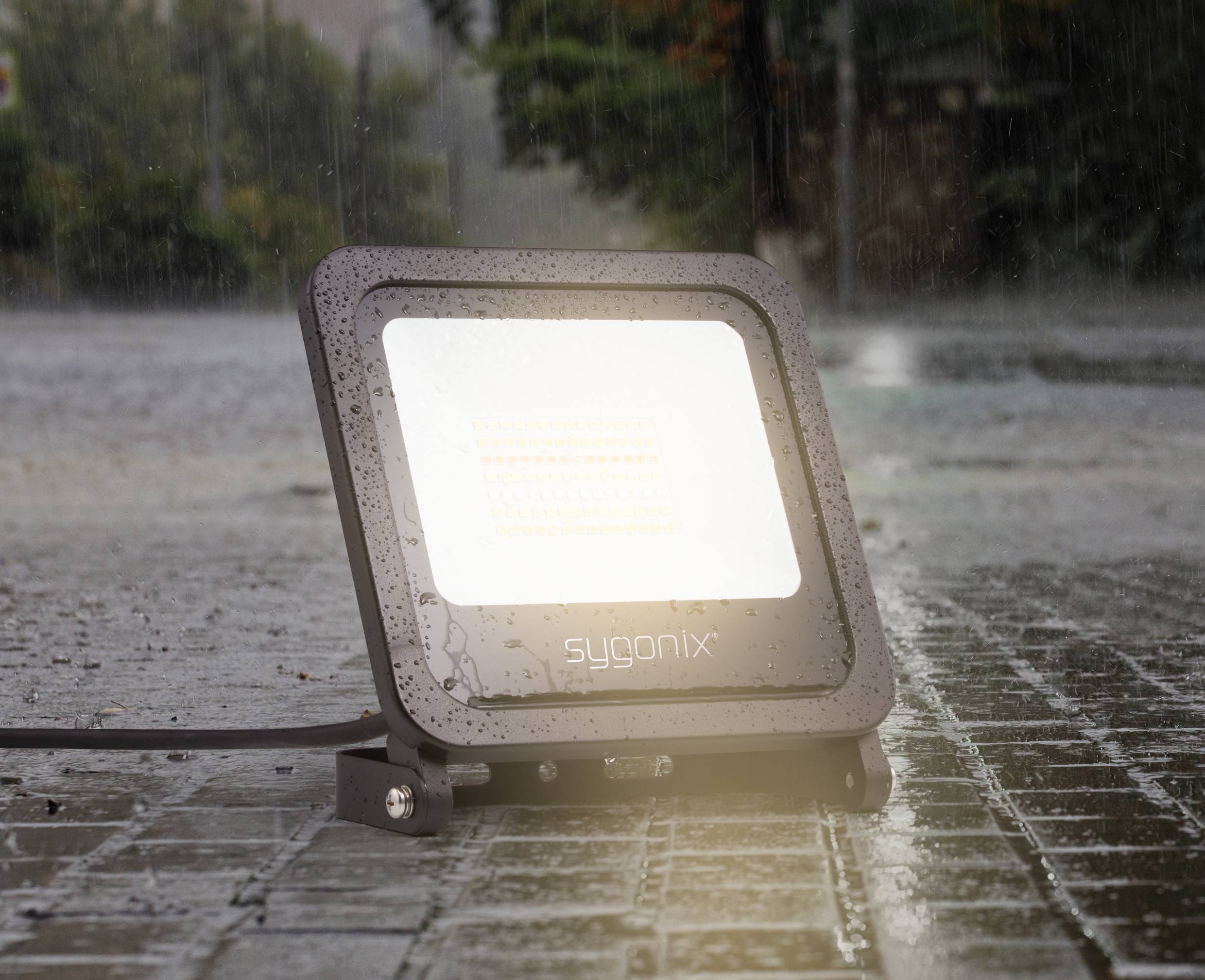 A waterproof, square spotlight shines brightly on a wet, rainy street.