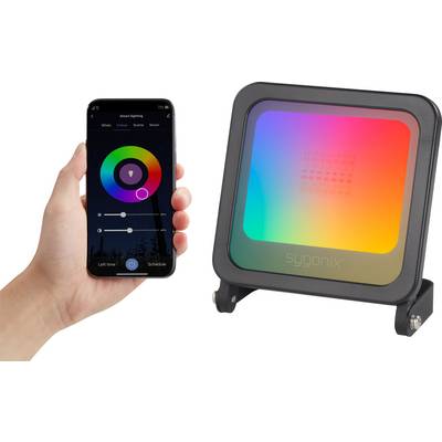 A hand is holding a smartphone with an app for controlling an LED floodlight. The floodlight is displaying a colourful gradient.