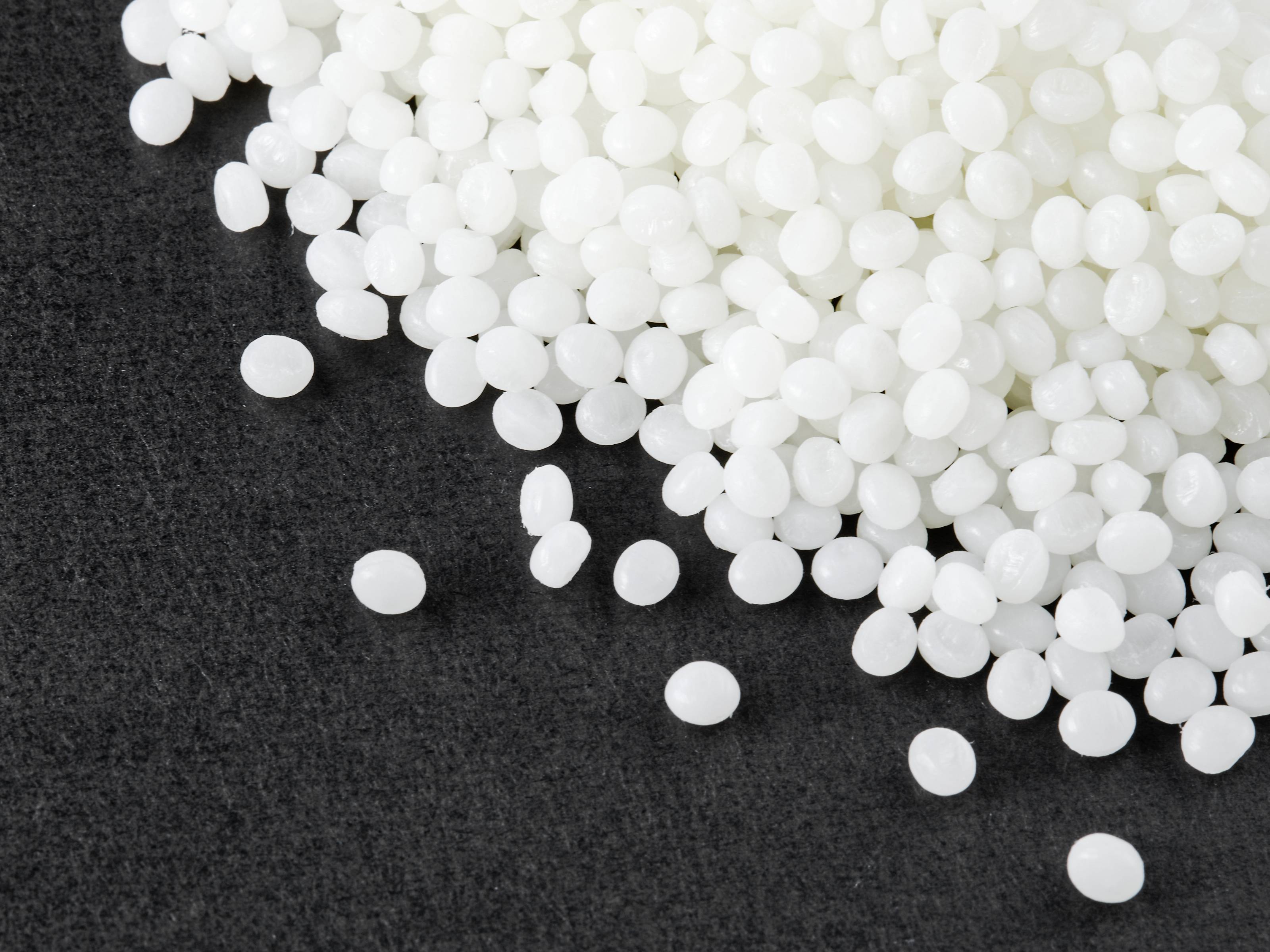 White plastic pellets are scattered across a grey surface.