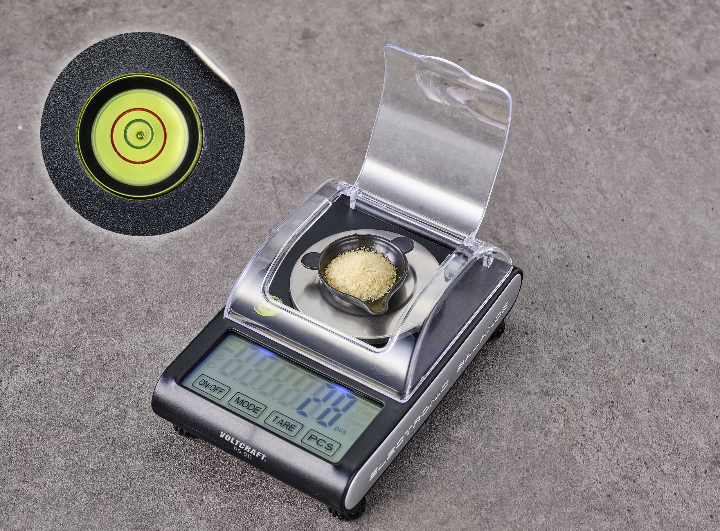 'Kitchen scales with a small container filled with brown sugar. Digital display shows weight. Close-up of a spirit level hole.'