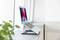 A laptop is sitting on an adjustable stand on a windowsill. The screen displays vibrant, blurry colours.