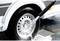 A pressure washer sprays water onto a car tyre to remove dirt. The tyre has a silver wheel with several holes.