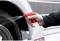 A hand is holding a spray bottle and spraying liquid onto a car tyre to clean the wheel.
