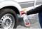 A person is spraying cleaning solution onto the wheel of a caravan. The cleaning solution is in a white and red spray bottle.
