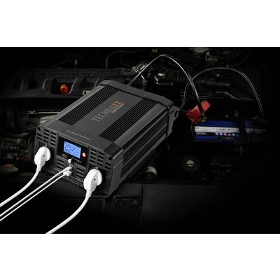 A Technaxx car battery charger shows the display with two connected cables leading to a car battery in the engine compartment.