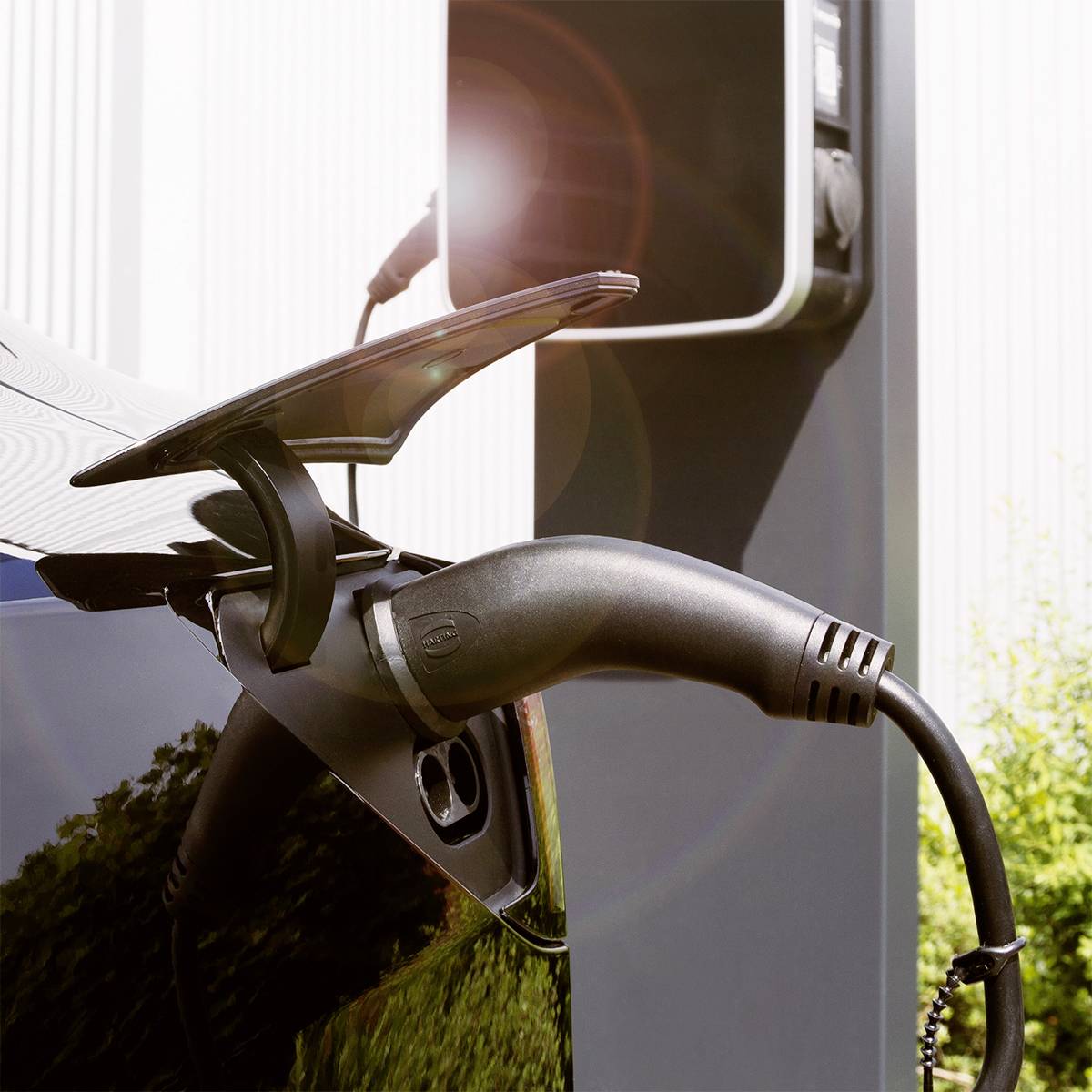 An electric car is being charged at a charging station. The charging cable is connected to the vehicle, ready for energy transfer.