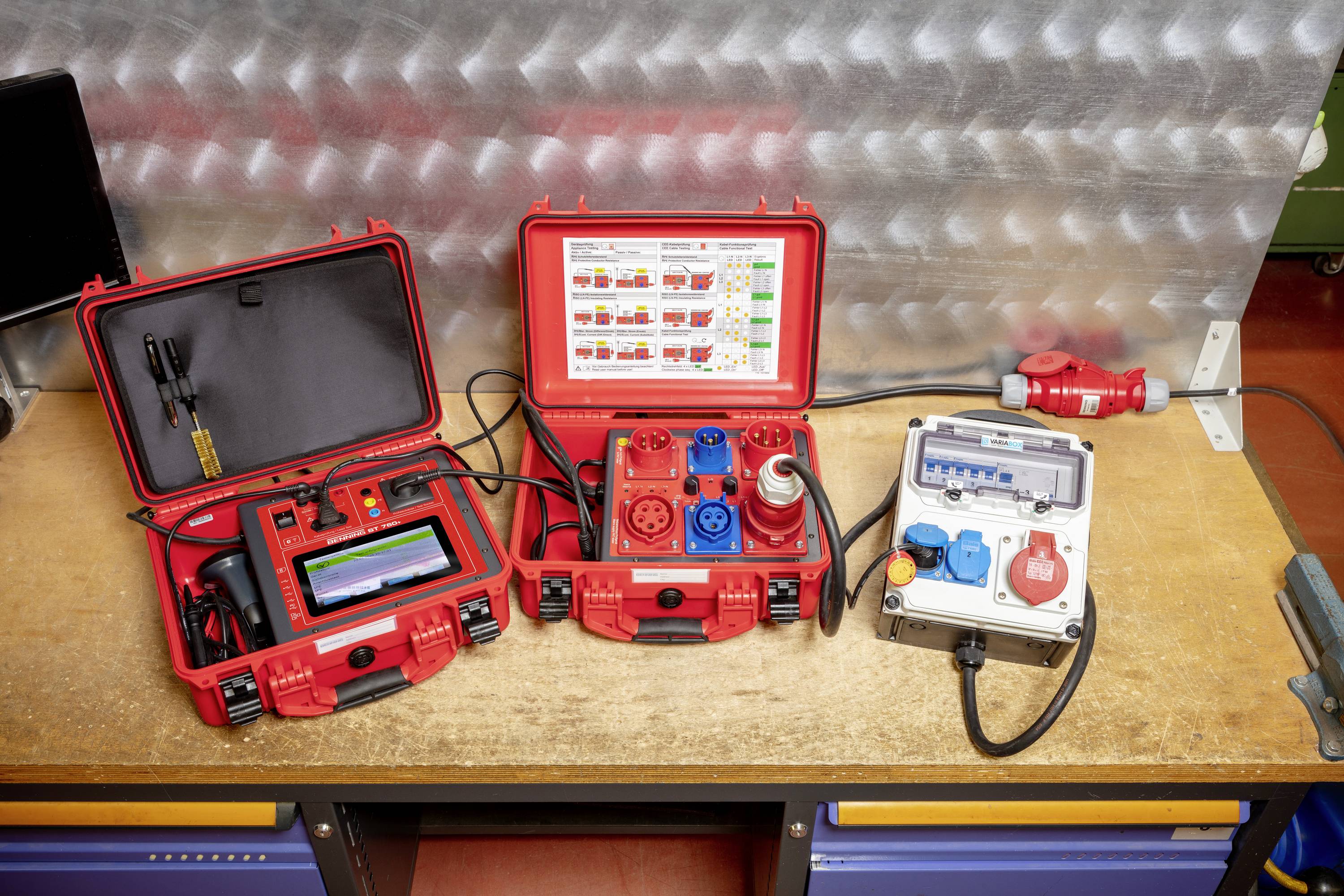 Toolbox with various electronic measuring instruments on a workbench. Each device has coloured connectors and displays.