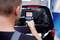 A man is measuring temperatures on a black vehicle using a digital device, possibly for inspection or maintenance.