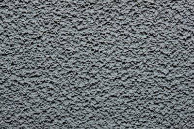 Rough, grey, textured concrete wall surface, conveying a sense of solidity and rawness.