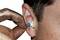 A person with a dirty finger is inserting a yellow earplug into their ear.